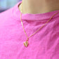 Gold plated necklace with a cheese plant leaf pendant on a pink shirt