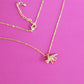 Gold plated necklace with a triceratops pendant on a pink background with the fine chain and lobster clasp visible.
